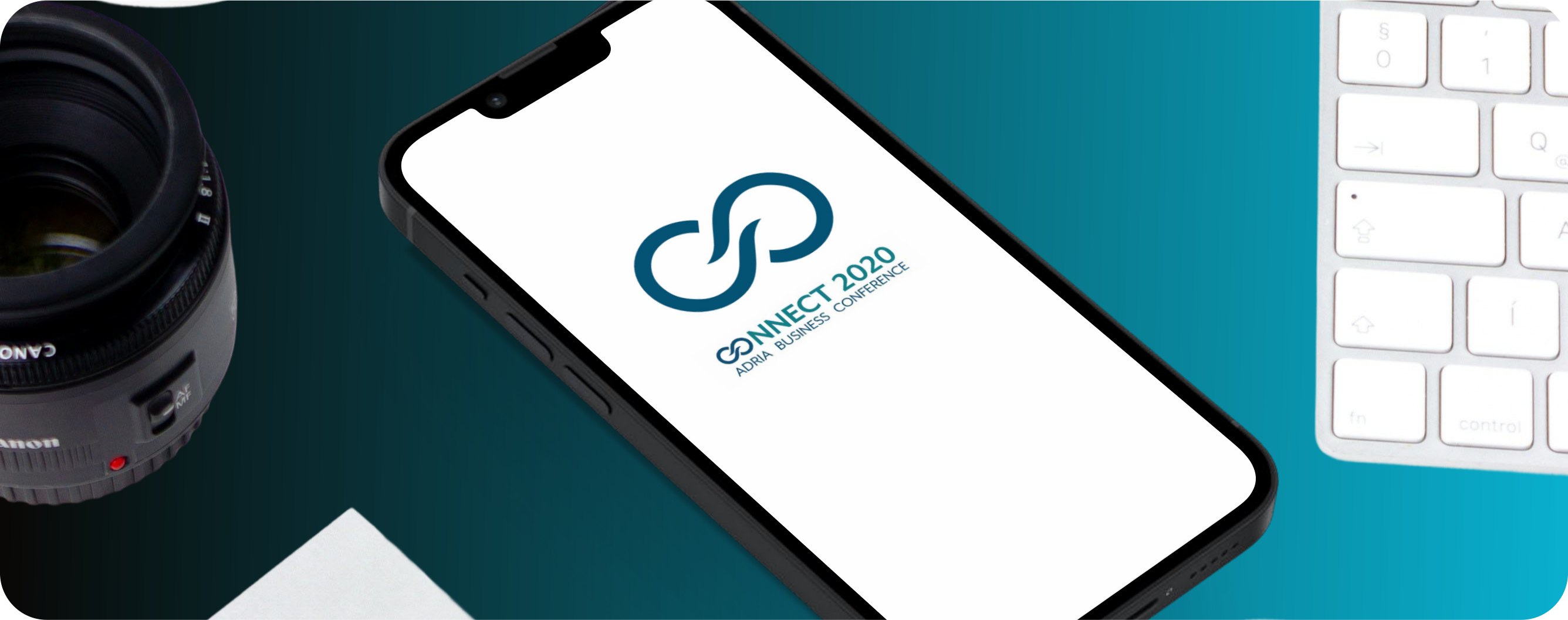 The Connect 2020 app open on a phone, beside a camera lens and keyboard